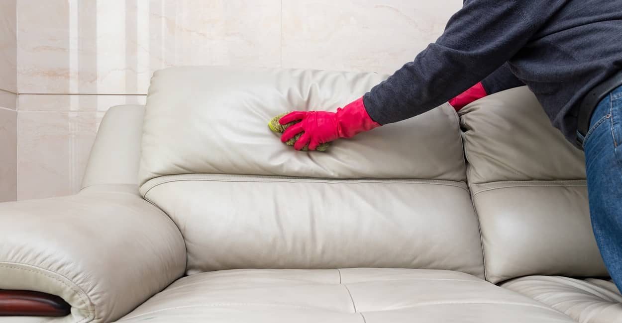 Frau beim Ledermöbel reinigen: hier das Sofa